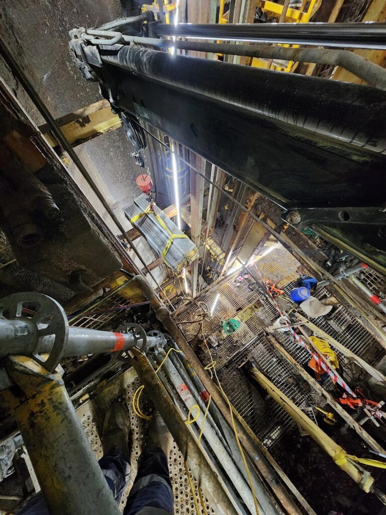 a view looking down at a large metal structure inside a mine shaft - Shaft Steel Replacement - Job Report 2024